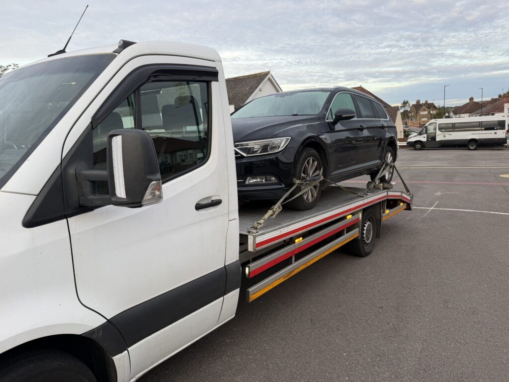 Recovery Car flatbed truck transporting a VW Passat to a dealer, London